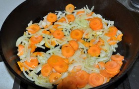 Пока в сковороде, поставленной на средний огонь, разогревается растительное масло, шинкуем луковицу четвертинками колец и натираем кружками морковь на терке для капусты (или обычной).