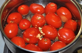 Закладываем помидоры порциями в кипящую воду. Через 1-2 минуты кипения кожица начинает лопаться, расходиться по надрезам.