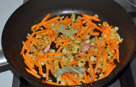 В ту же сковороду засыпаем лук и морковь. Обжариваем, помешивая, 3-4 минуты. На дольках чеснока оставляем только нижний слой шелухи, слегка раздавливаем ножом и добавляем в сковороду вместе с лаврушкой.