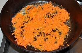 Пока на среднем огне разогревается толстодонная сковорода с растительным маслом, быстро очищаем и натираем мелко и тонко морковь. Добавляем в сковородку сливочное масло, закипело – кладем морковь, тонкие волокна которой меняют цвет, пока она 5-6 минут  пассеруется . 