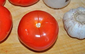 Чтобы удалить ненужную кожицу, делаем на томатах крестообразные надрезы. 