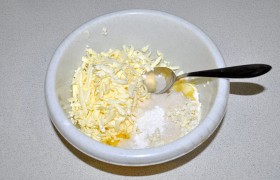 Разминаем вилкой прямо в миске творог, добавляем 1 яйцо и белок второго (желток оставляем для обмазки), соль, ванилин,  2-3 ст. ложки сахара. Натираем на крупной терке сливочное масло.