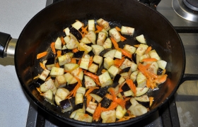 2 ст. ложки растительного масла разогреваем на огне между сильным и средним, выкладываем баклажан и морковь, постоянно перемешивая, обжариваем 4-5 минут.