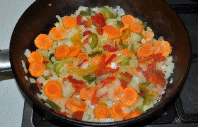 Вторую конфорку занимаем еще одной сковородой, в которой на среднем огне сначала 5-6 минут  пассеруем  лук и морковь, затем добавляем  сладкий перец, посыпаем хмели-сунели, орегано и уцхо сунели, солим.